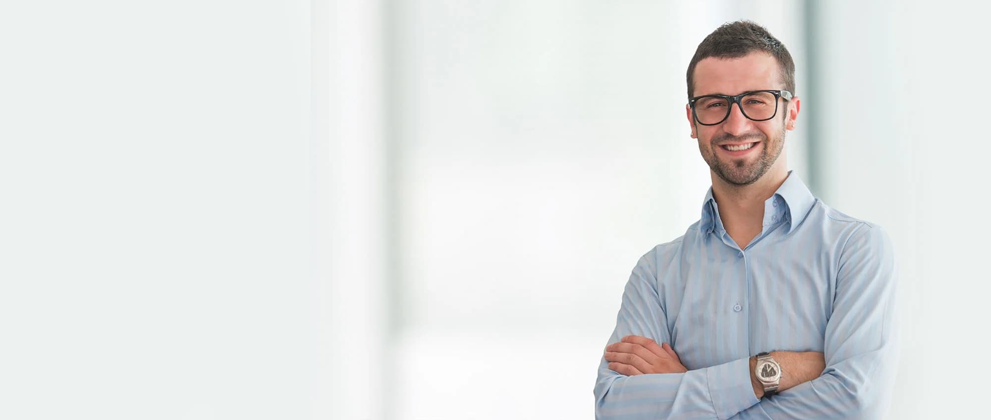 Mężczyzna w biurze z założonymi rękami.